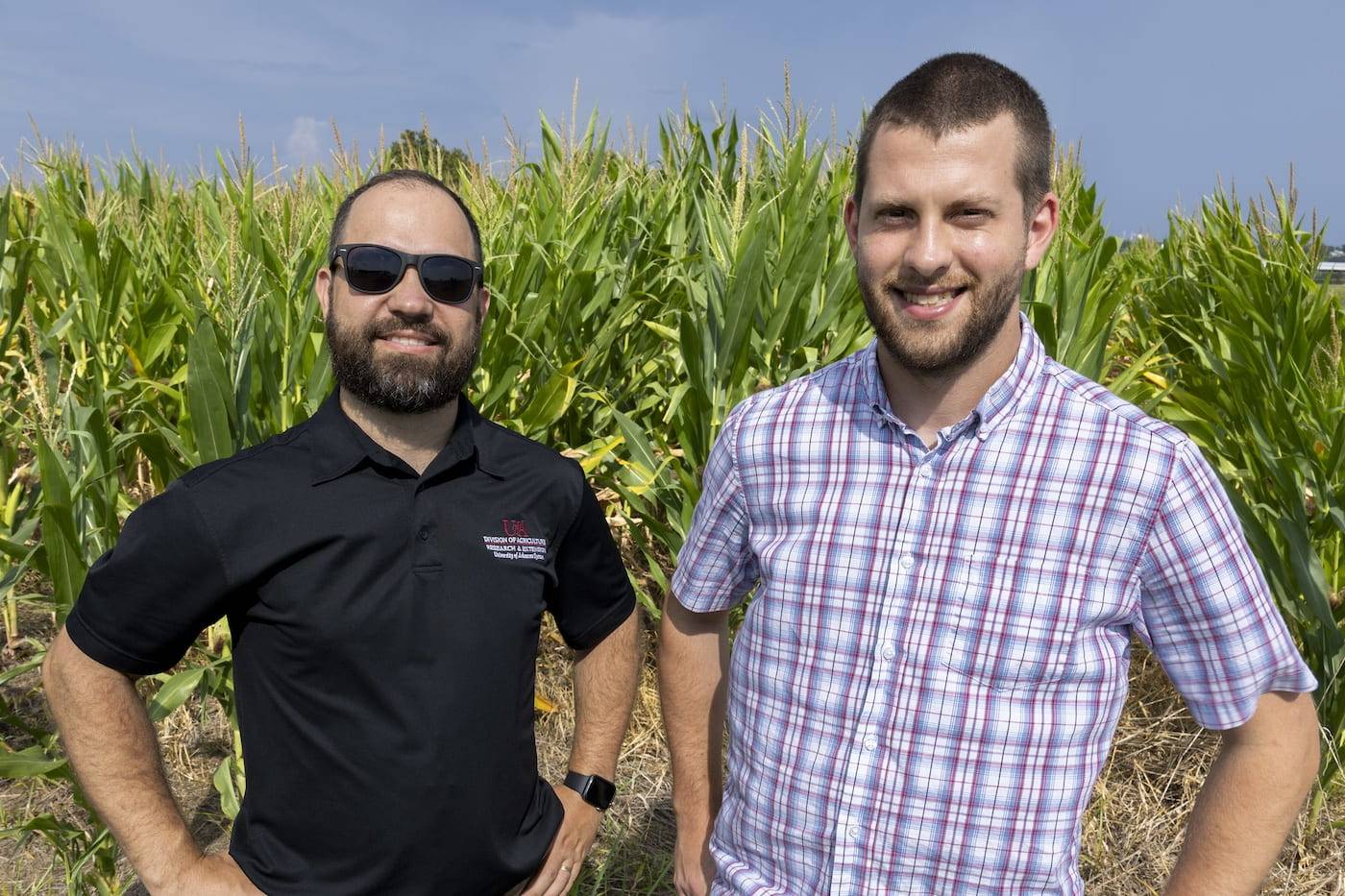 Samuel Fernandes and Igor Fernandes smiling, standing in front of corn in the field.